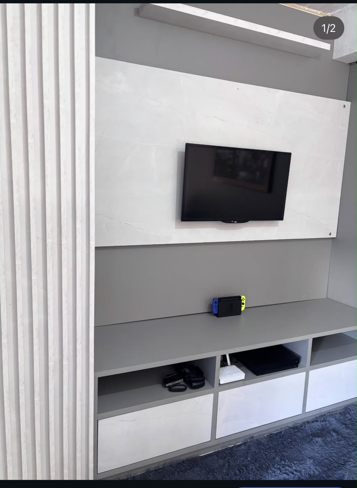Painel para TV em tons claros com ripado lateral e rack com nichos