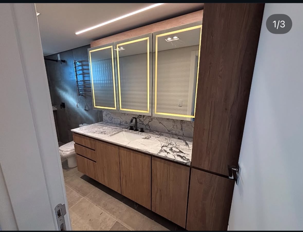Móvel de banheiro amadeirado com coluna lateral e três espelhos iluminados