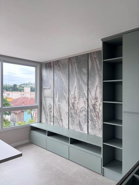 Móvel verde com nichos e painel junto à janela