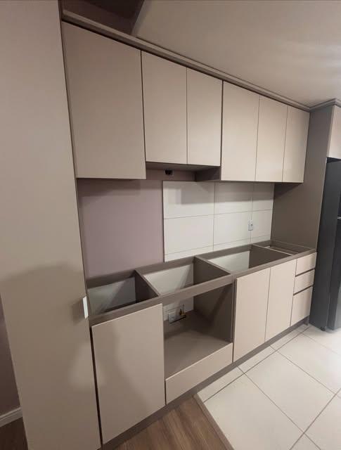 Armários de cozinha em tons claros com bancada e espaço para eletrodomésticos