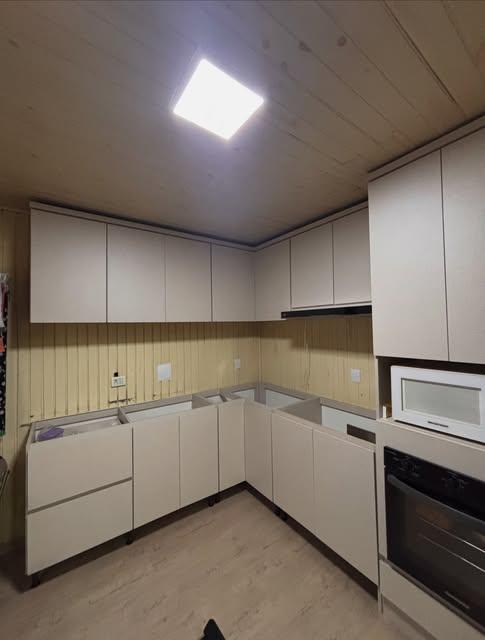 Cozinha planejada em L com móveis claros e forno embutido
